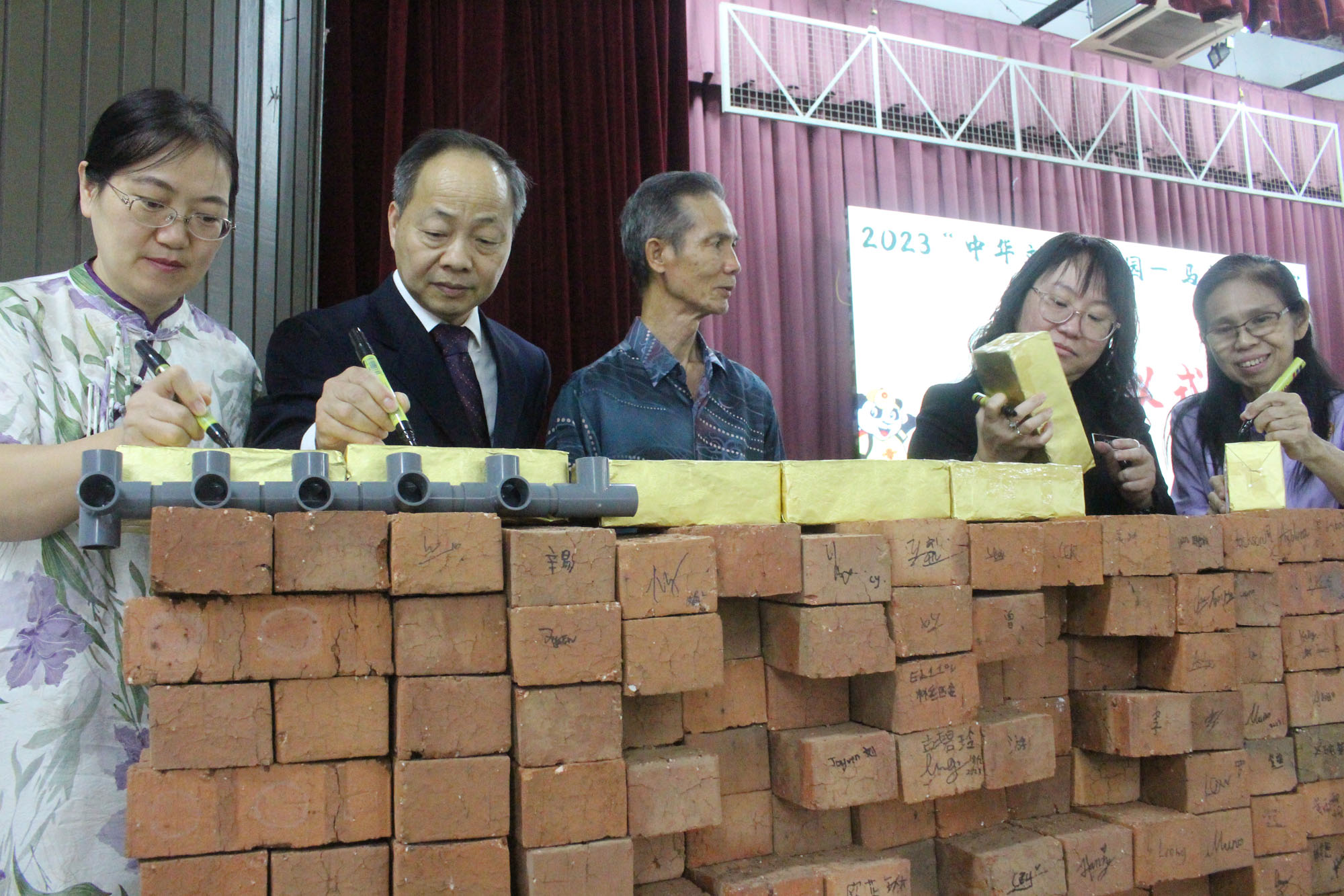 五位嘉宾把名字签在金砖上，以作纪念